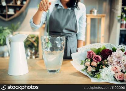 Female florist adds fertilizer to the water for flowers. Floristry service, floristic business, floral shop. Florist adds fertilizer to the water for flowers