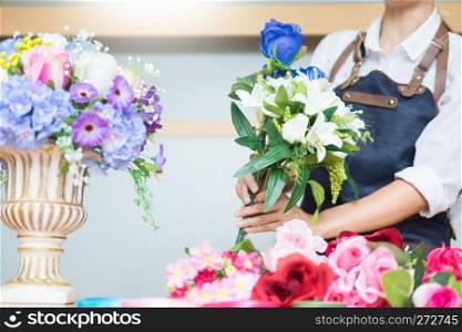 Female Florist at work using Arranging making beautiful Artificial bouquet vest at flower shop, business, sale and floristry craft and hand made concept