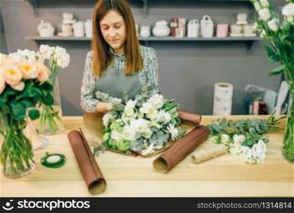 Female florist decorate fresh flower composition. Floral business, bouquet preparation process, materials and tools for decoration on the table. Female florist decorate fresh flower composition