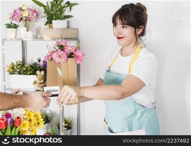 female florist giving flower paper bag her customer