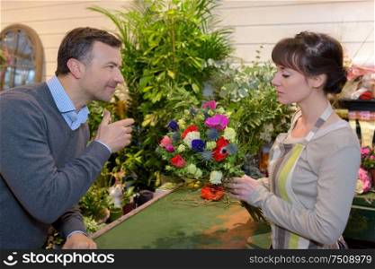 female florist giving flower to customer in the flower shop