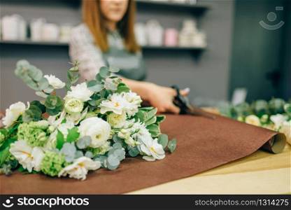Female florist hands cuts flower decoration with scissors. Floral business, bouquet preparation process. Female florist hands cuts decoration with scissors