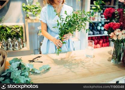 Female florist holds fresh flowers in floral shop. Floristry business, bouquet making. Female florist holds fresh flowers in floral shop