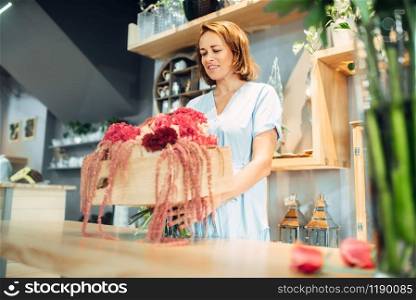 Female florist puts fresh flowers in a vase in floral shop. Floristry service, floristic business. Female florist puts flowers in a vase, floral shop
