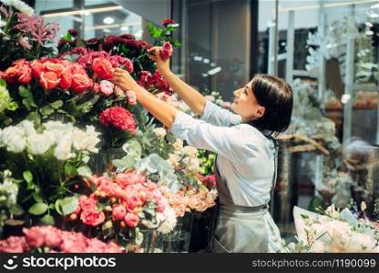 Female florist selects flowers for making a bouquet in floral shop. Floristry service, floristic business