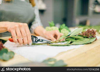 Female florist with pruner in hands makes flower bouquet. Floral business, decoration tools