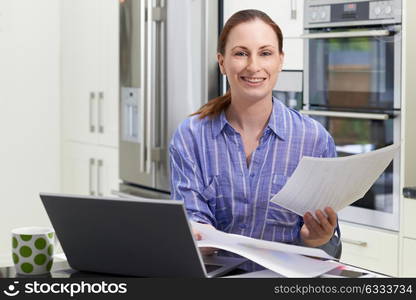 Female Freelance Worker Using Laptop In Kitchen At Home