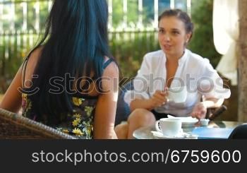 Female friends chat over a hot drink in outdoor cafe
