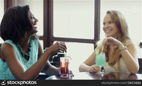 Female friends drinking cocktails and talking in a pub