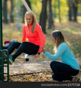 Female Friends Exercising in Public Park. Woman Doing Exercise for Legs on Machine. Autumn, Fall.. Female Friends Exercising in Public Park. Autumn, Fall.