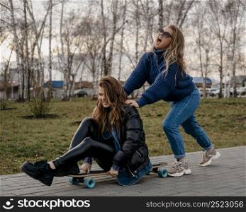female friends having fun outdoors with skateboards