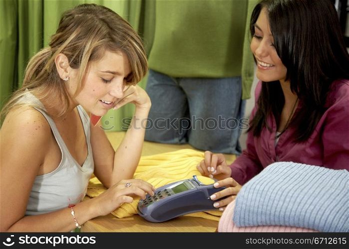 female friends in a retail store smiling and buying some clothes