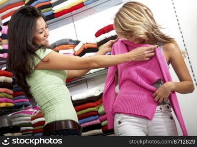 female friends in a retail store smiling and buying some clothes
