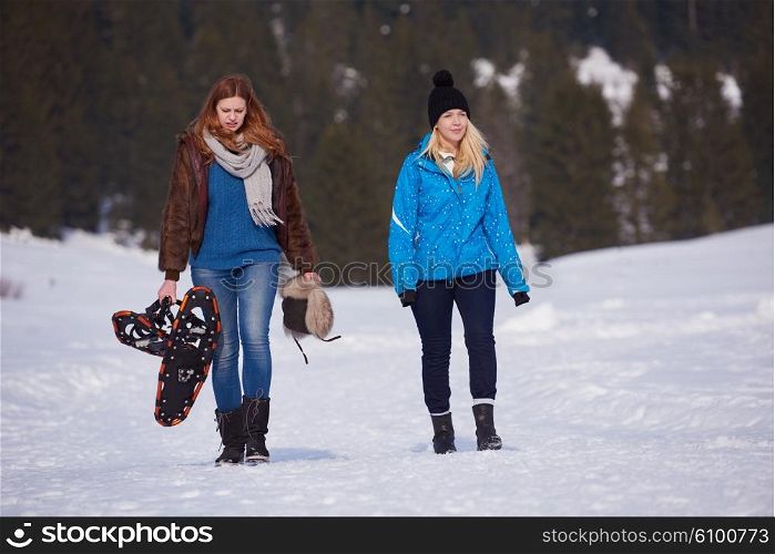 female friends in beautiful winter day have relaxed walk on snow and. holding snowshoes