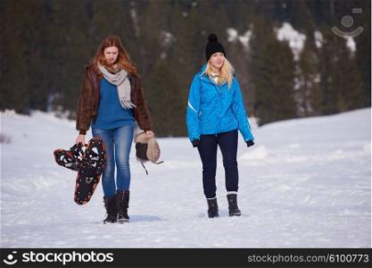 female friends in beautiful winter day have relaxed walk on snow and. holding snowshoes