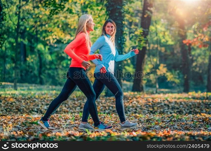 Female Friends Jogging in Public Park. Autumn, Fall.