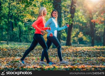 Female Friends Jogging in Public Park. Autumn, Fall.