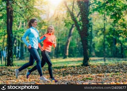 Female Friends Jogging Outdoors in a Public Park. Autumn, Fall.. Friends Jogging Outdoors in a Public Park. Autumn, Fall.