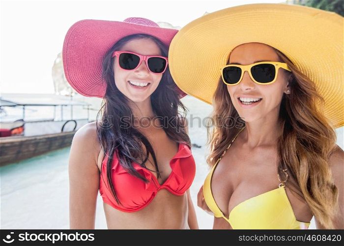 Female friends on vacation. Happy smiling female friends in bikini and sunhats on vacation