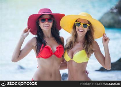 Female friends on vacation. Happy smiling female friends in bikini and sunhats on vacation