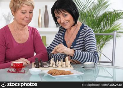 Female friends playing chess over coffee