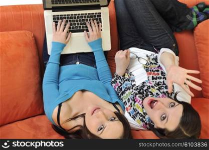 female friends relax and working on laptop computer at home on orange sofa isolated on white backgrond