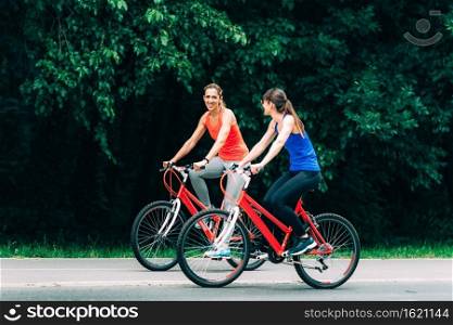 Female Friends Riding Bikes Together in Park