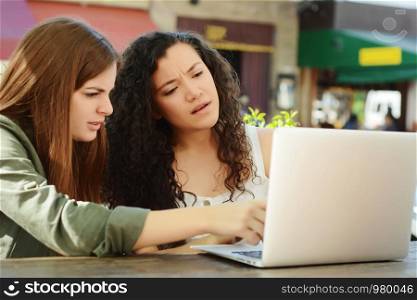 Female friends studying and learning with a laptop in a coffee shop. Education concept.