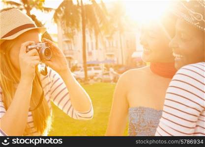 Female Friends Taking Photographs Of Each Other In Park