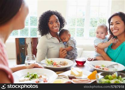 Female Friends With Babies Enjoying Meal At Home Together