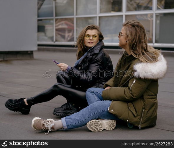 female friends with smartphone outdoors together