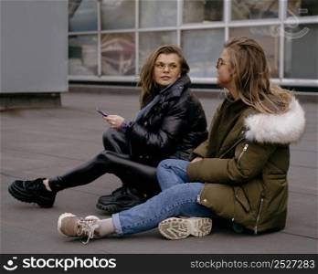 female friends with smartphone outdoors together