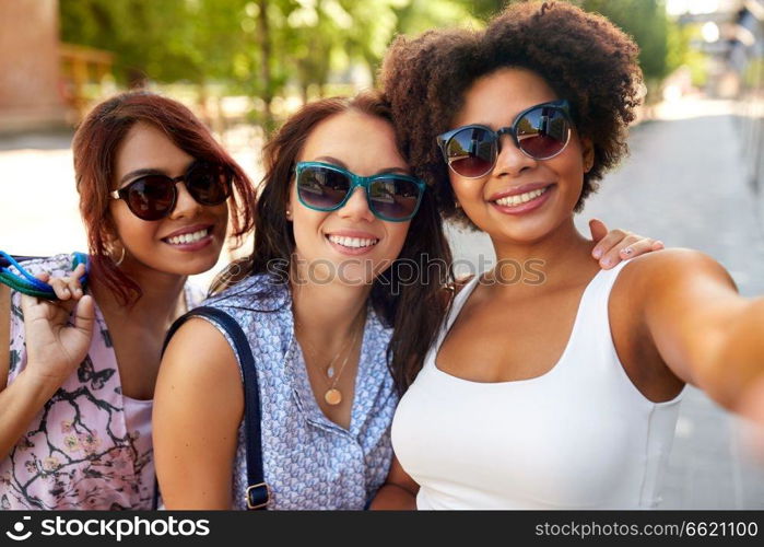 female friendship, people and leisure - happy young women in sunglasses at summer park. happy young women in sunglasses at summer park