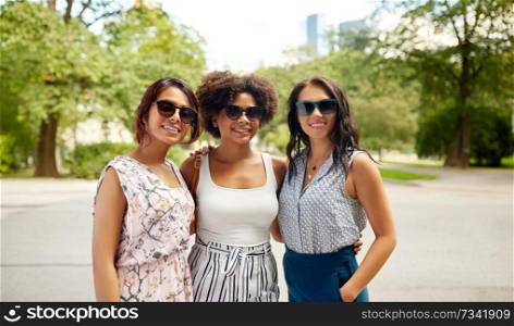 female friendship, people and leisure - happy young women in sunglasses at summer park. happy young women in sunglasses at summer park