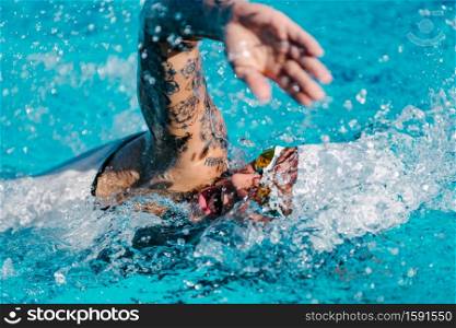 Female front crawl swimmer with tattoos during training
