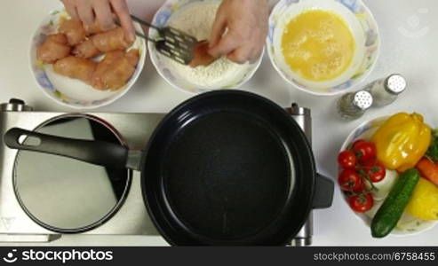 Female frying chicken breast roll on a pan. Shoot from above