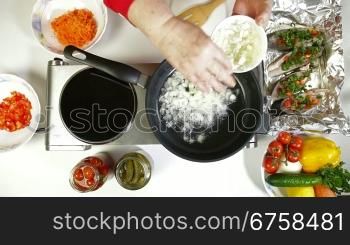 Female frying chopped onion in a frying pan. Shoot from above