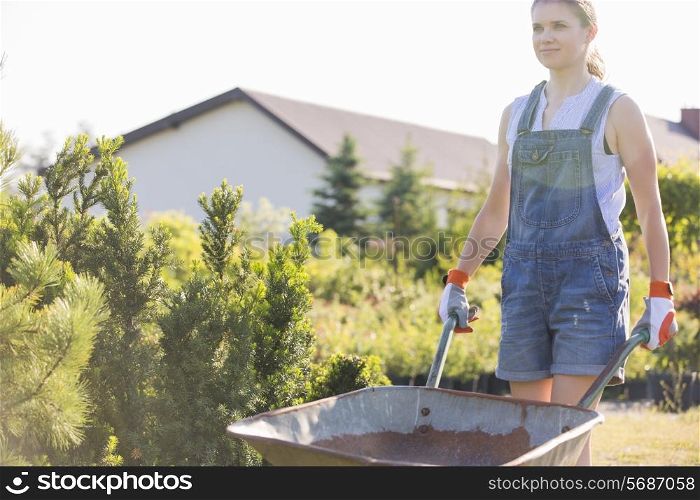 Female gardener pushing wheelbarrow at plant nursery