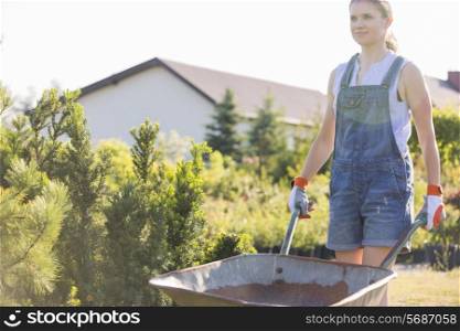Female gardener pushing wheelbarrow at plant nursery
