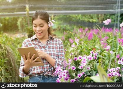 Female gardeners wear plaid shirts. There were orchids picking up the ears, the hand holding the tablet and pointing fingers on the tablet and smiling with joy.