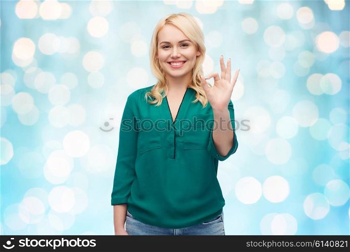 female, gender, gesture, plus size and people concept - smiling young woman in shirt and jeans showing ok hand sign over blue holidays lights background