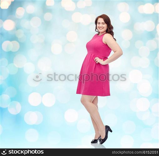 female, gender, portrait and people concept - smiling happy young plus size woman posing in pink dress background over blue holidays lights background