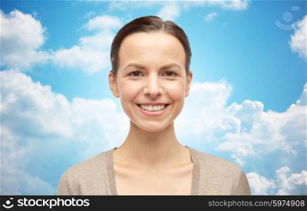 female, gender, portrait and people concept - smiling young woman in cardigan over blue sky and clouds background