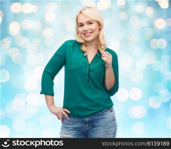 female, gender, portrait, plus size and people concept - smiling young woman in shirt and jeans over blue holidays lights background