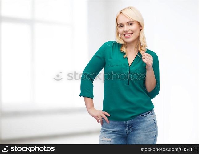 female, gender, portrait, plus size and people concept - smiling young woman in shirt and jeans over white room background
