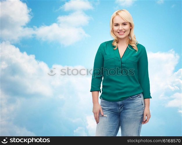female, gender, portrait, plus size and people concept - smiling young woman in shirt and jeans over blue sky and clouds background