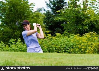 Female golfer swining her club on the fairway