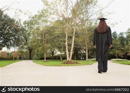 Female graduate walking down a path