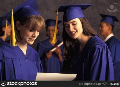 Female Graduates Looking At Diploma