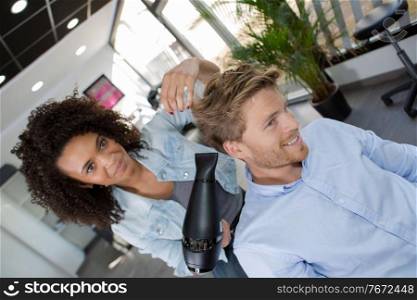 female hairdresser blow drying male clients hair